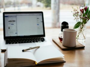 Laptop, notes i długopis na biurku – symbol pracy online i sesji hipnoterapii prowadzonych zdalnie.